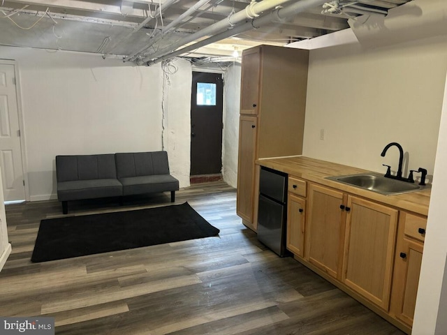 kitchen featuring dark hardwood / wood-style floors, butcher block countertops, sink, and black refrigerator