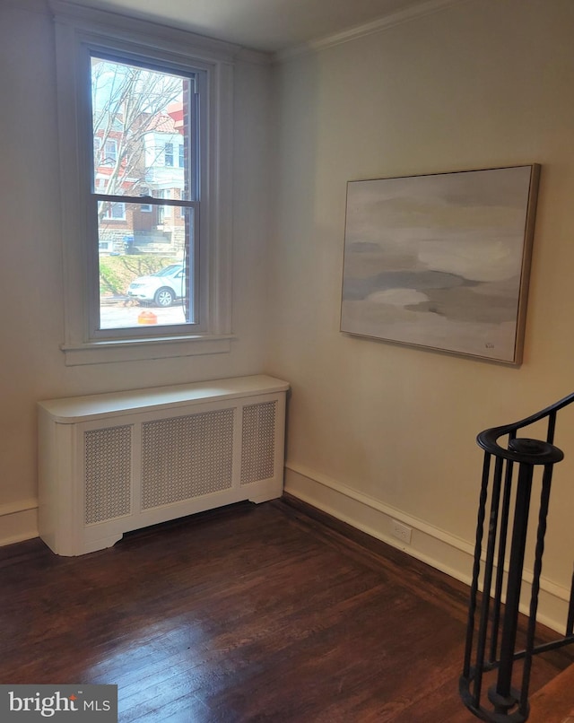 interior space with radiator heating unit, ornamental molding, and dark wood-type flooring