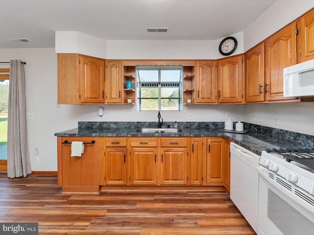 kitchen featuring dark stone countertops, sink, light hardwood / wood-style floors, and white appliances