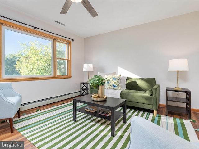 living room featuring ceiling fan, a baseboard heating unit, and dark hardwood / wood-style floors