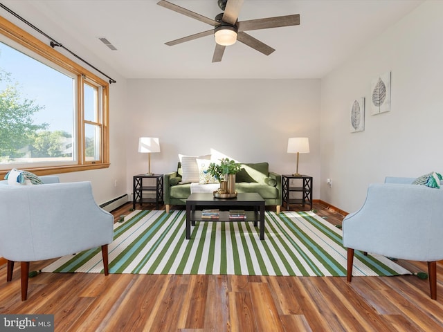 sitting room with hardwood / wood-style floors, a baseboard heating unit, and ceiling fan