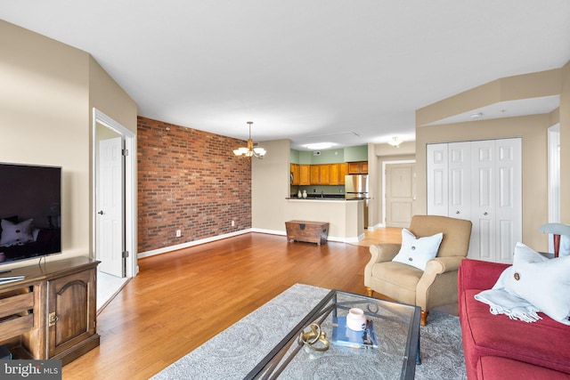 living room featuring a notable chandelier, light hardwood / wood-style floors, and brick wall