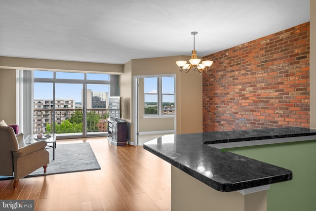 kitchen featuring pendant lighting, light wood-type flooring, kitchen peninsula, and an inviting chandelier