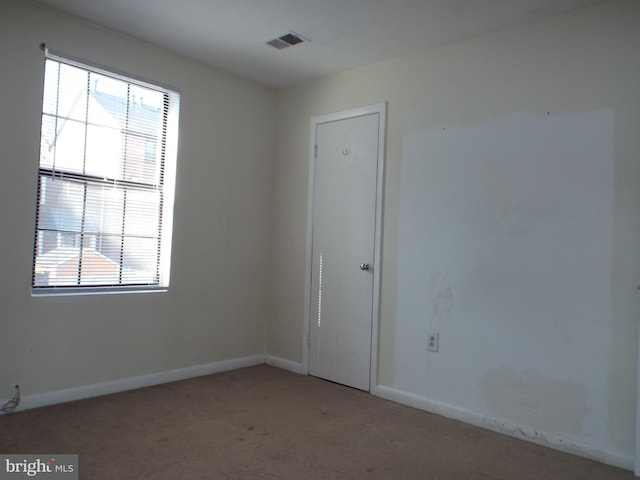 spare room with light carpet, baseboards, and visible vents