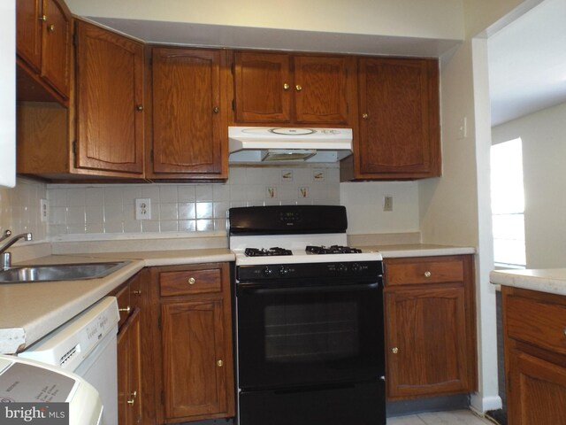 kitchen featuring dishwasher, a sink, light countertops, under cabinet range hood, and gas range oven