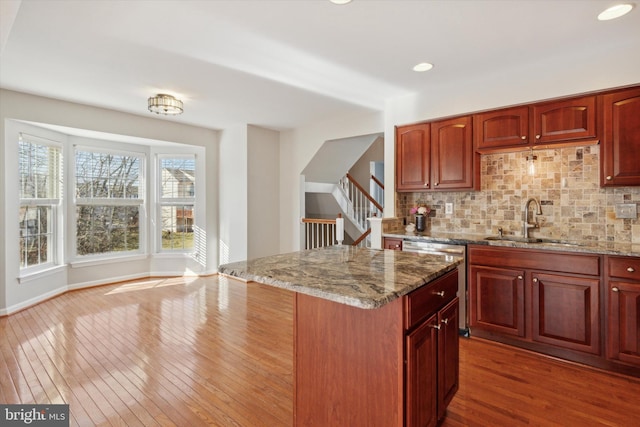 kitchen with light stone countertops, dark hardwood / wood-style floors, tasteful backsplash, and sink