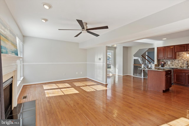 unfurnished living room featuring ceiling fan, sink, and hardwood / wood-style flooring