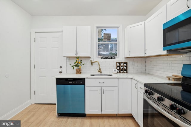 kitchen with decorative backsplash, appliances with stainless steel finishes, light wood-type flooring, sink, and white cabinets