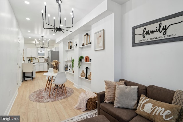 living room with a notable chandelier, built in features, and light hardwood / wood-style flooring