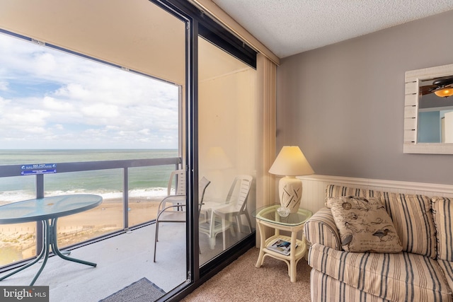 sitting room featuring a beach view, a textured ceiling, carpet, and a water view