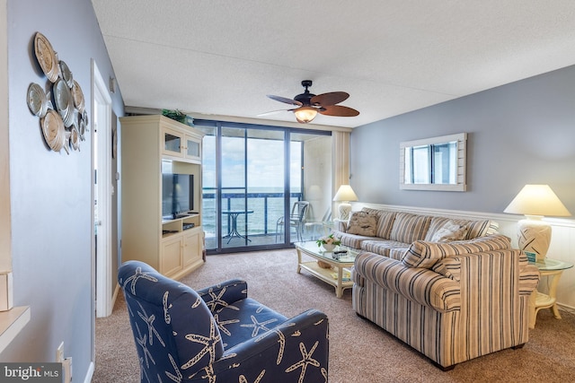 carpeted living room featuring ceiling fan, a textured ceiling, and expansive windows