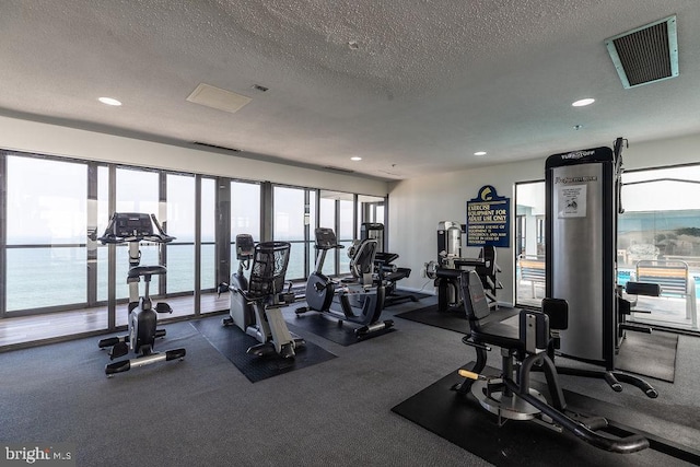 gym featuring a water view and a textured ceiling