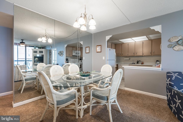 carpeted dining space featuring a textured ceiling, ceiling fan with notable chandelier, and sink