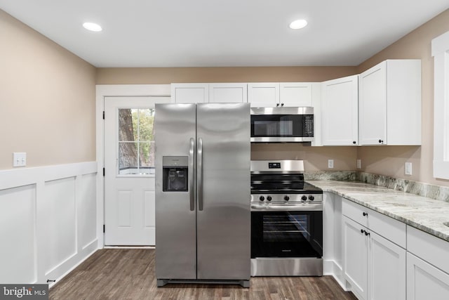 kitchen featuring appliances with stainless steel finishes, light stone counters, dark hardwood / wood-style floors, and white cabinets