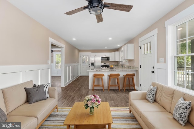 living room featuring ceiling fan, dark hardwood / wood-style floors, and sink