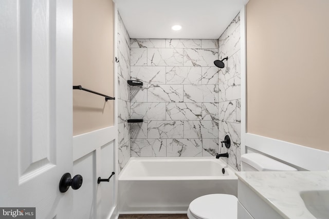 full bathroom featuring tiled shower / bath combo, vanity, and toilet