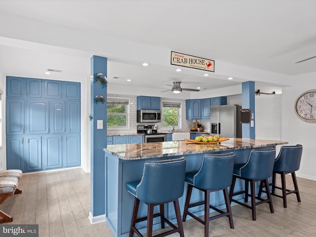 kitchen with appliances with stainless steel finishes, a barn door, stone counters, and light hardwood / wood-style flooring