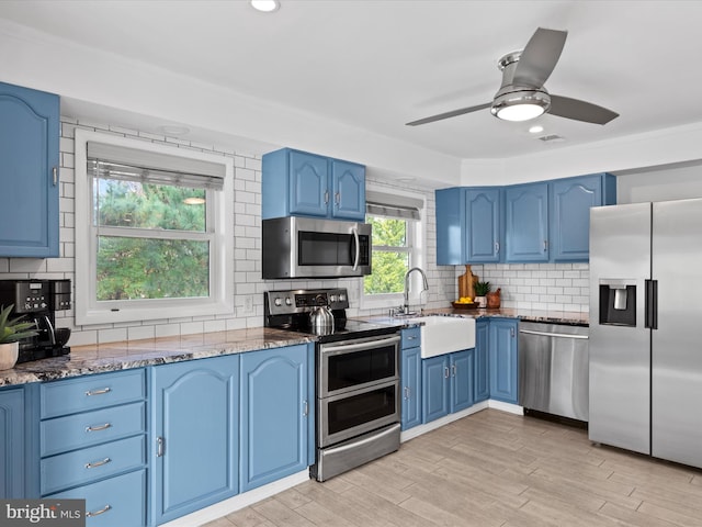 kitchen featuring stainless steel appliances, plenty of natural light, and blue cabinets