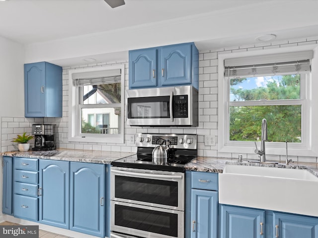 kitchen with blue cabinetry, appliances with stainless steel finishes, and a healthy amount of sunlight