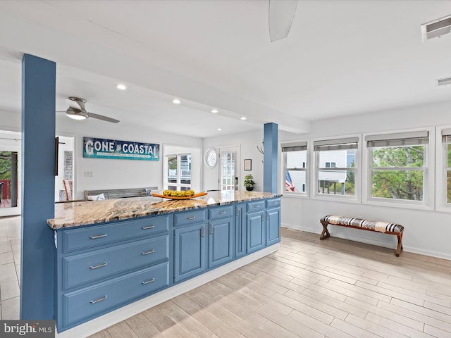 kitchen featuring light stone countertops, blue cabinetry, light hardwood / wood-style flooring, and ceiling fan