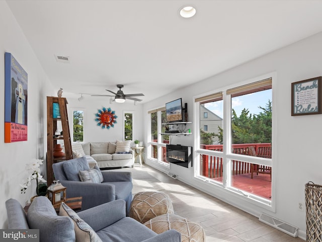 living room with ceiling fan, light wood-type flooring, and a wealth of natural light