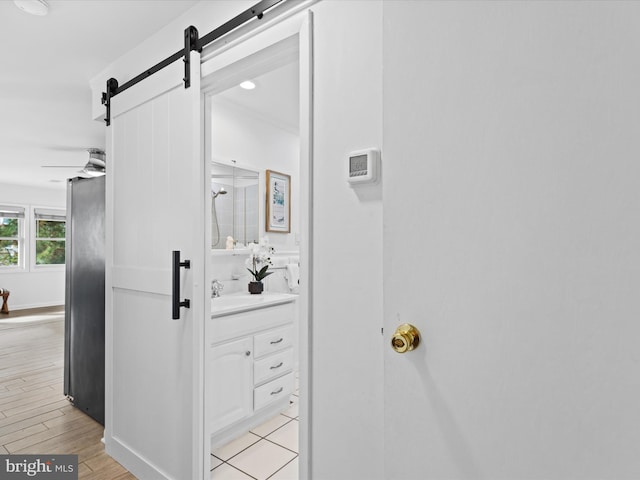 interior details with wood-type flooring, a barn door, and ceiling fan