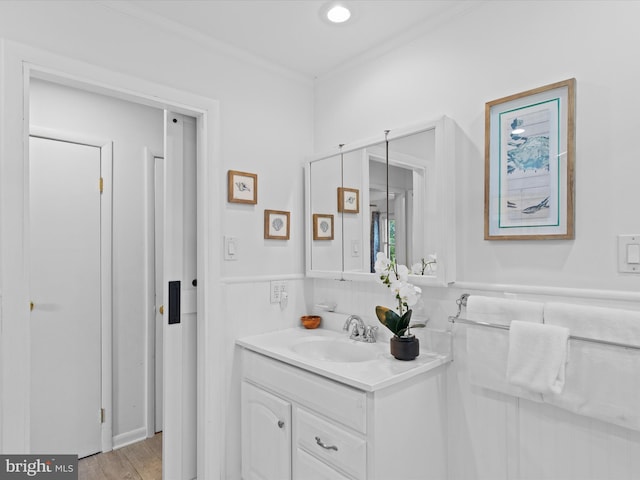 bathroom featuring vanity, ornamental molding, and hardwood / wood-style flooring