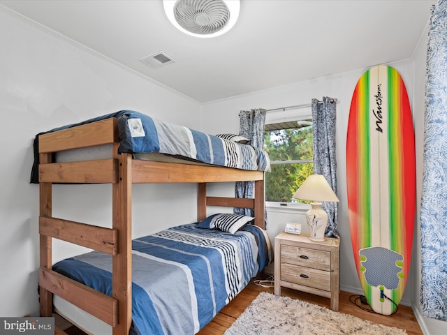 bedroom featuring wood-type flooring and ornamental molding