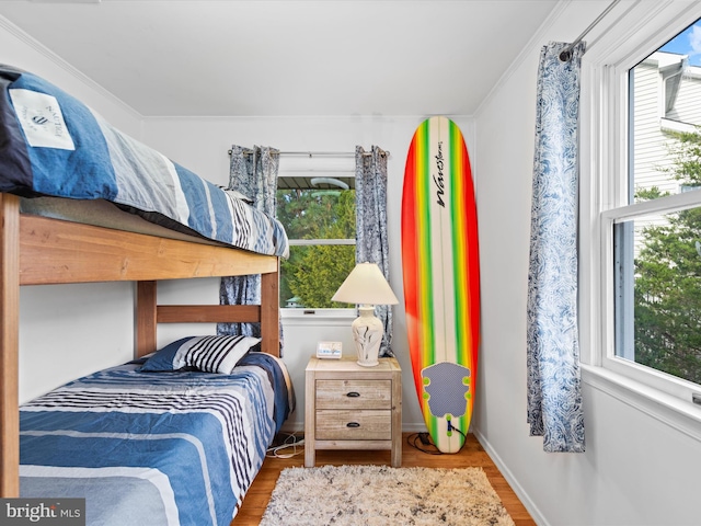 bedroom featuring ornamental molding, multiple windows, and hardwood / wood-style floors