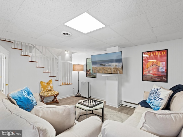 living room featuring baseboard heating, a paneled ceiling, and light hardwood / wood-style floors