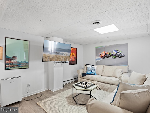 living room featuring baseboard heating, a drop ceiling, and light hardwood / wood-style floors