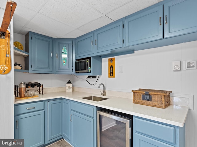 kitchen featuring a drop ceiling, sink, light hardwood / wood-style floors, wine cooler, and blue cabinets