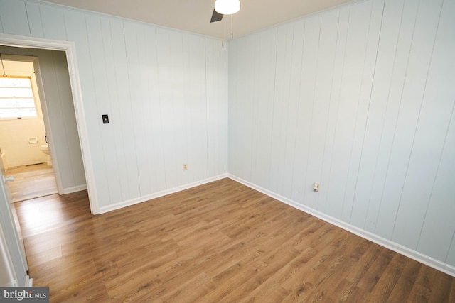 spare room featuring ceiling fan, hardwood / wood-style floors, and wood walls