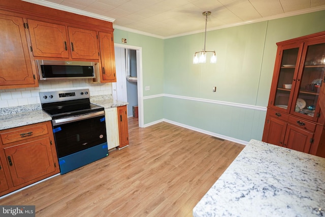 kitchen featuring stainless steel appliances, light hardwood / wood-style floors, a chandelier, pendant lighting, and ornamental molding