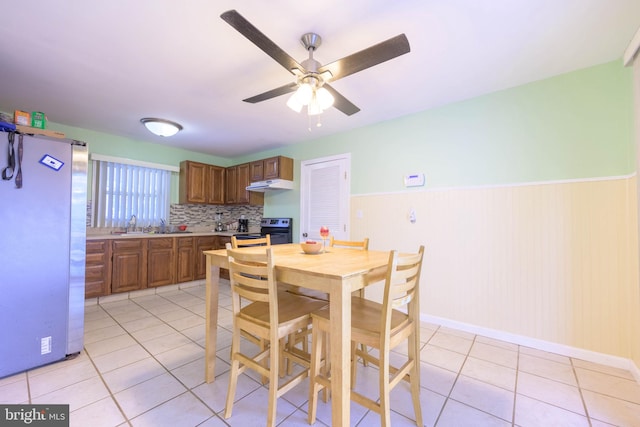 tiled dining room featuring ceiling fan and wood walls