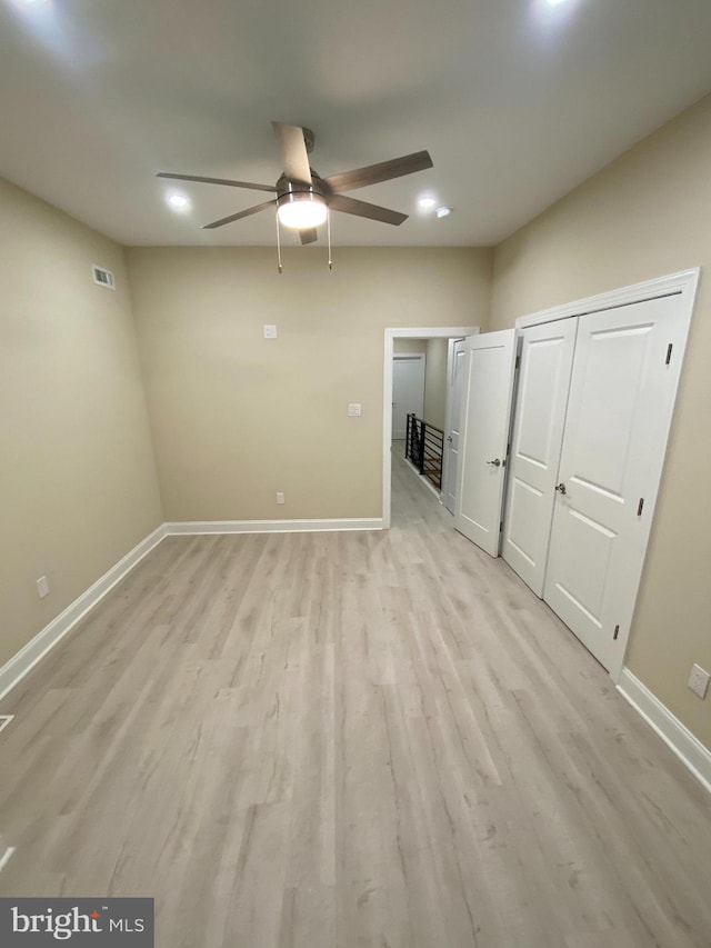 unfurnished bedroom with multiple closets, light hardwood / wood-style flooring, and ceiling fan