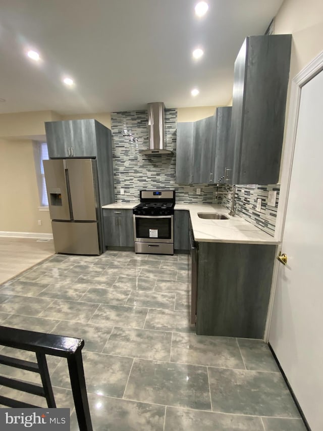 kitchen featuring wall chimney exhaust hood, appliances with stainless steel finishes, sink, and tasteful backsplash