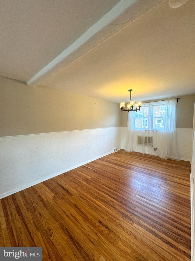 interior space with hardwood / wood-style flooring, beam ceiling, a notable chandelier, and an AC wall unit