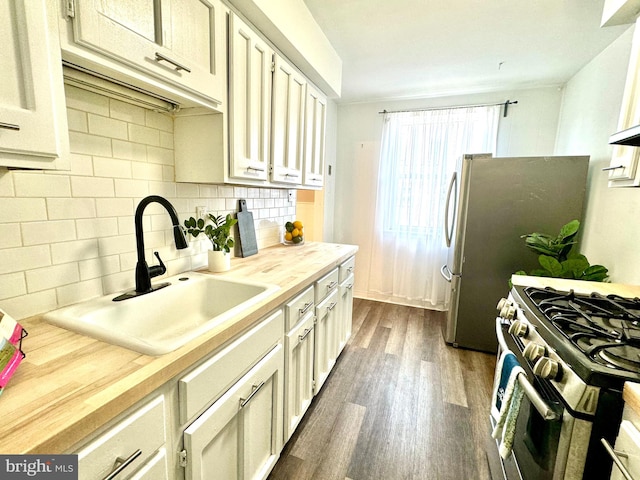 kitchen featuring appliances with stainless steel finishes, dark wood-type flooring, backsplash, wooden counters, and sink