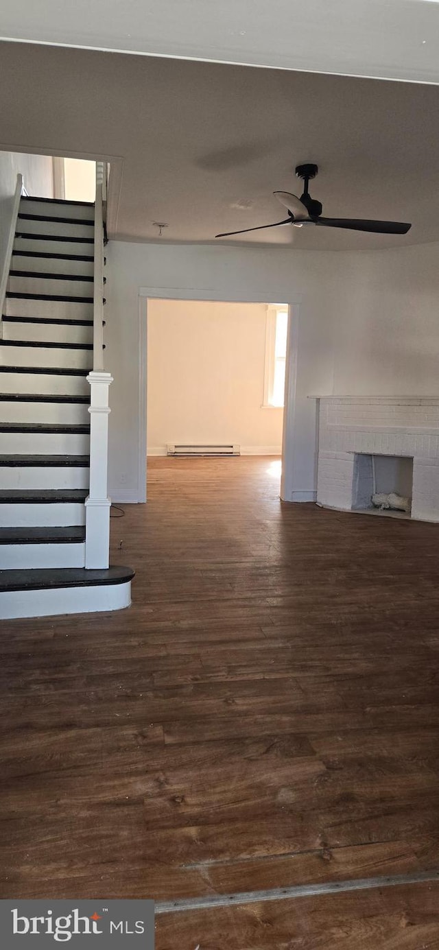 unfurnished living room with ceiling fan, a baseboard radiator, a fireplace, and dark wood-type flooring