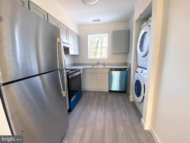 1294 Cooper St Unit C06, Edgewater Park, NJ 08010 - kitchen featuring stainless steel appliances, stacked washer / drying machine, under cabinet range hood, a sink, and light countertops