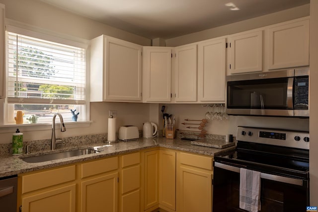 kitchen with light stone counters, stainless steel appliances, and sink