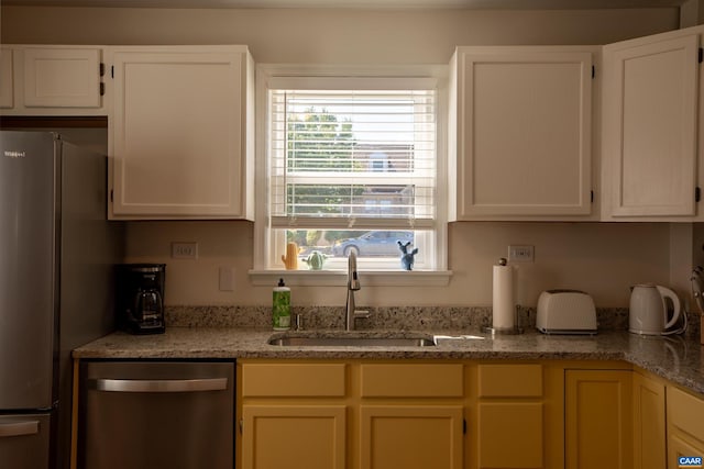 kitchen featuring light stone counters, stainless steel appliances, sink, and white cabinetry