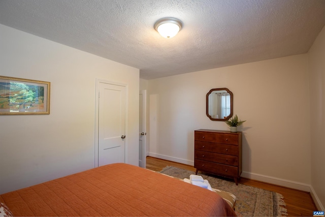 bedroom featuring a textured ceiling and light hardwood / wood-style flooring