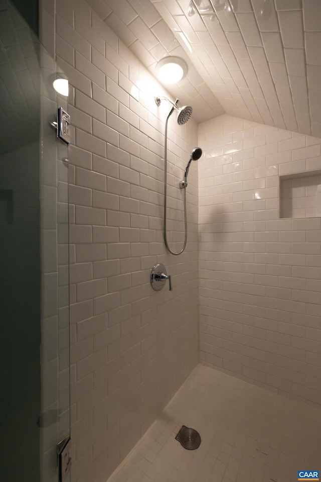 bathroom featuring a tile shower and vaulted ceiling