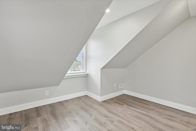 additional living space with light wood-type flooring and vaulted ceiling