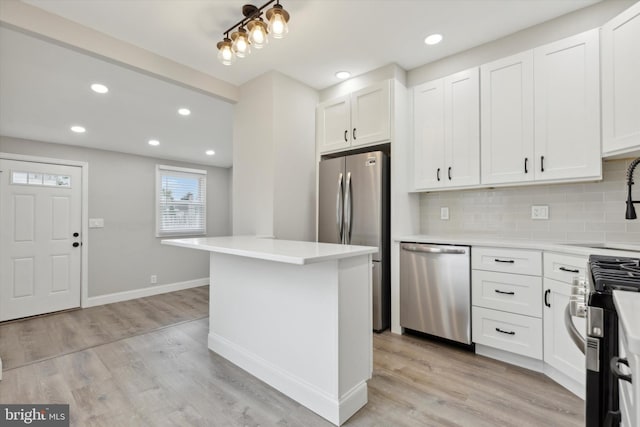 kitchen featuring stainless steel appliances, white cabinetry, light hardwood / wood-style floors, and backsplash