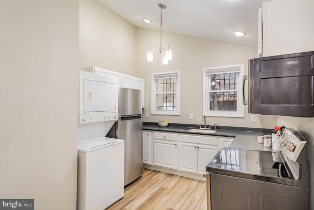 washroom featuring stacked washer and dryer, light hardwood / wood-style floors, sink, and a notable chandelier