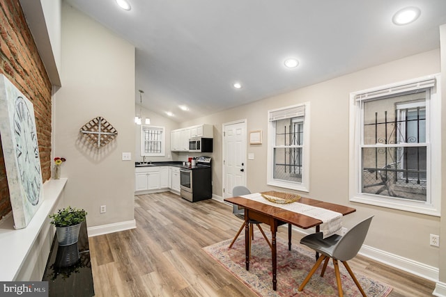 dining room featuring lofted ceiling, sink, and light hardwood / wood-style floors