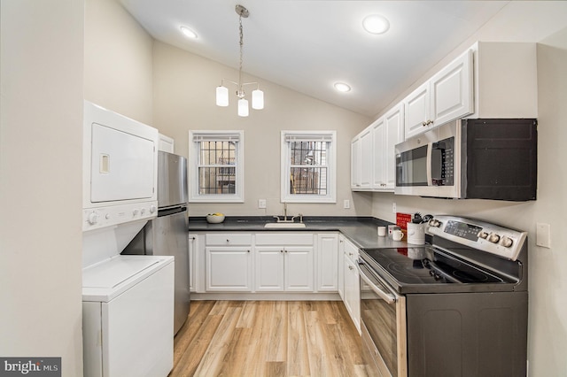 kitchen featuring white cabinetry, stacked washer / drying machine, hanging light fixtures, and appliances with stainless steel finishes